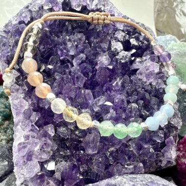 Zbliżenie bransoletki Harmonii Czakr z kamieni w odcieniach ziemi i światła.